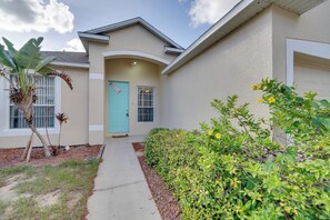 A residential building with a light-colored exterior, a turquoise door, and a pathway leading to the entrance. - Private Lanai! Gated Davenport Retreat (Davenport)