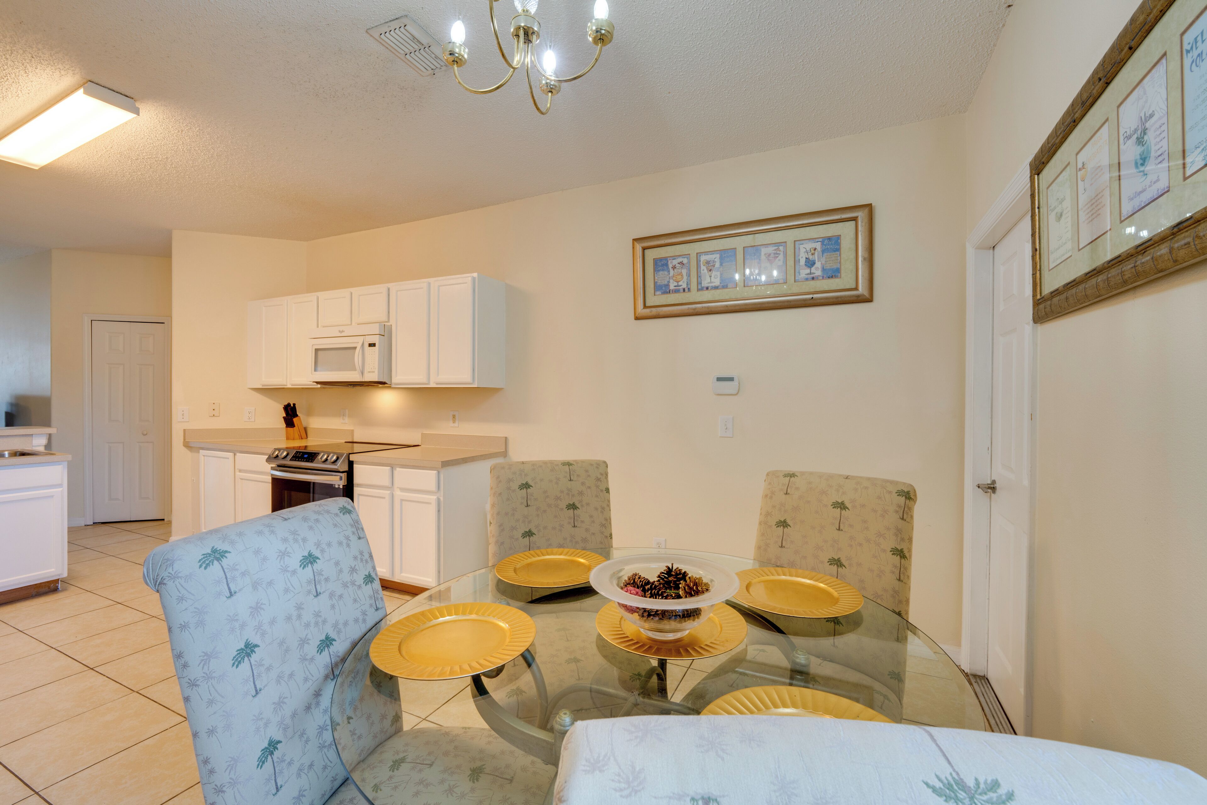 A dining area with a glass table surrounded by chairs, a microwave, and a framed certificate on the wall.
