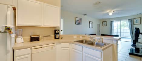 A kitchen with white cabinets, a dishwasher, a coffee maker, and a sink.