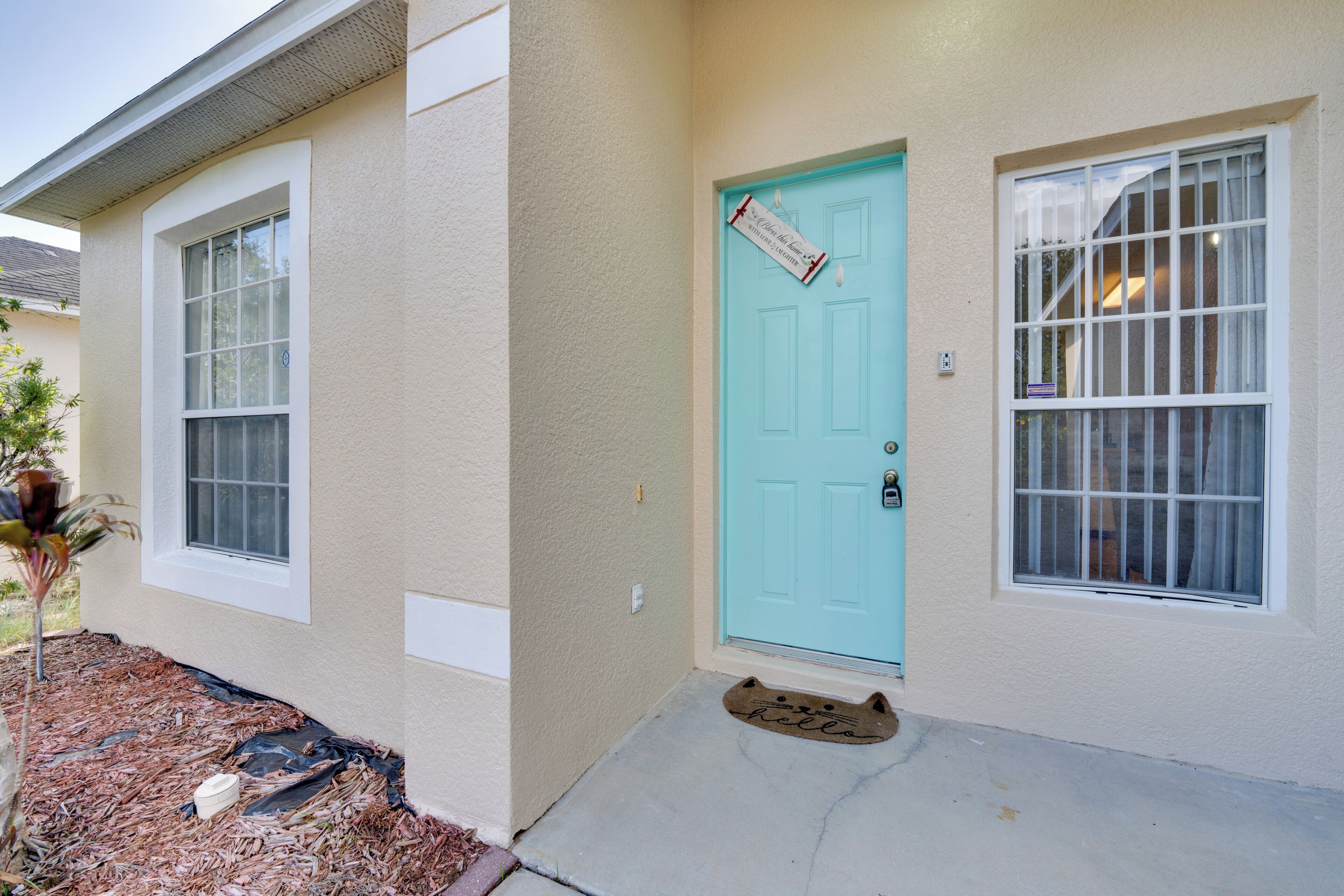 A house with a turquoise door, a window with a metal gate, and a doormat with the word "hello".