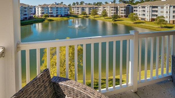 A balcony with a view of a lake, surrounded by multi-story buildings with balconies. - Pool Access & Balcony: Modern Myrtle Beach Condo (Myrtle Beach)