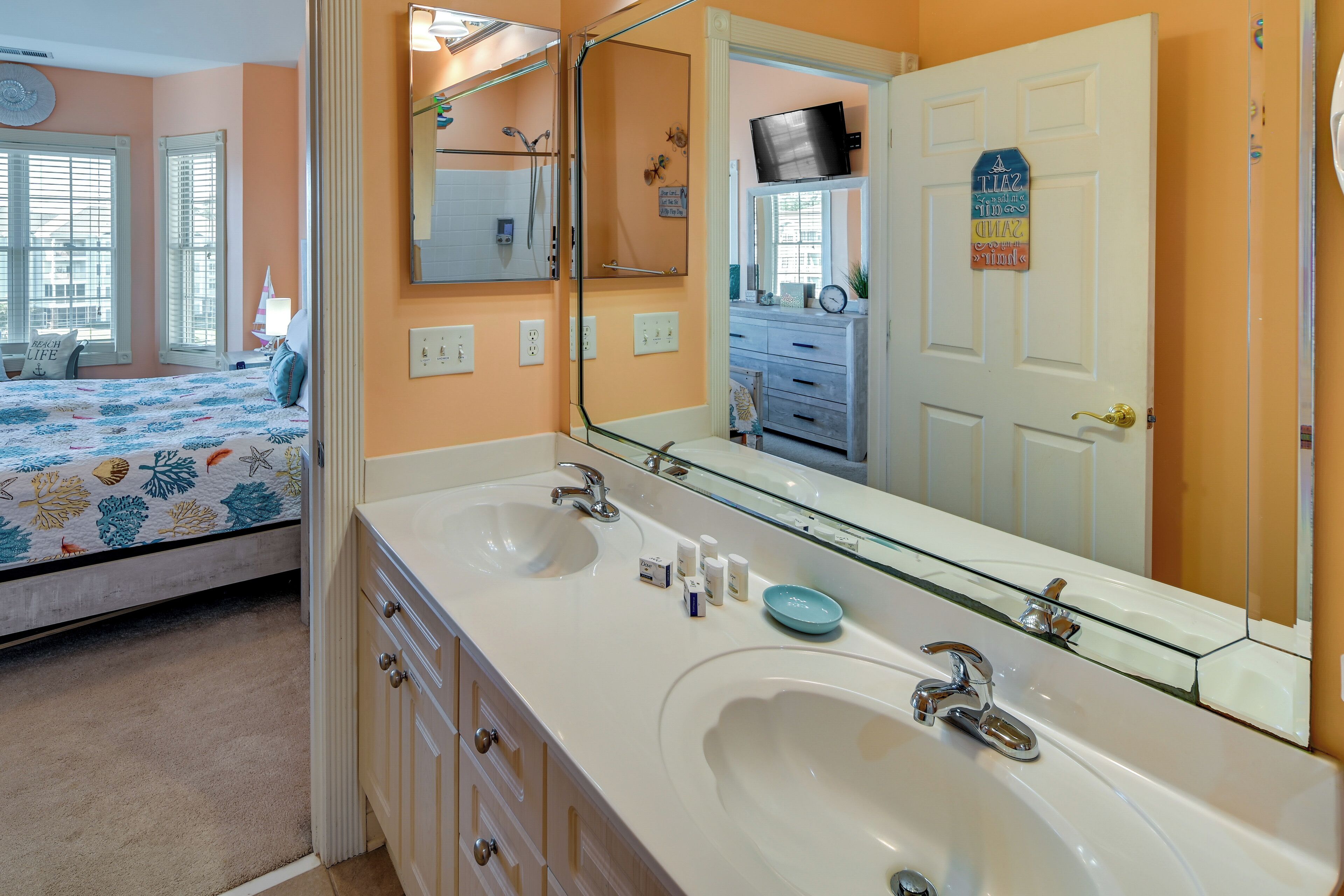 A bathroom with two sinks, a large mirror, and a shower area.