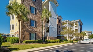 A multi-story building with a brick facade, balconies, and a parking lot. - Pool Access & Balcony: Modern Myrtle Beach Condo (Myrtle Beach)