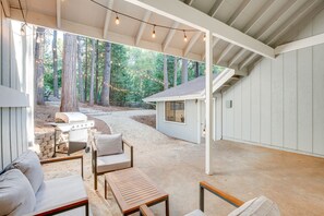 Un espace extérieur aménagé en terrasse, avec un barbecue, des sièges et une vue sur une forêt.