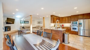 A modern kitchen with wooden cabinets, stainless steel appliances, and a dining area with a large table and chairs. - Pollock Pines Cabin: Game Room w/ A/C & Heat! (Pollock Pines)