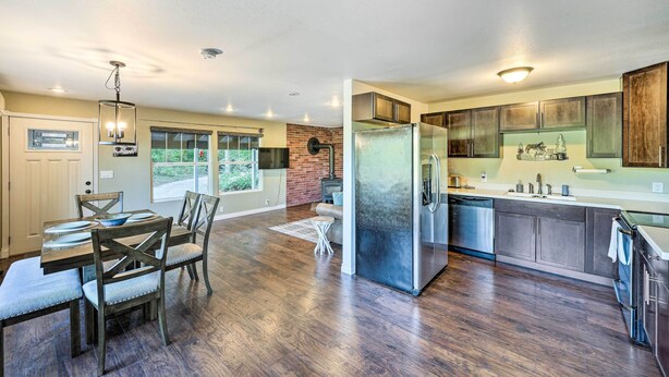 A modern kitchen with a central island, stainless steel appliances, and a view to the outside. - Dreamy Riverside Cabin With Fireplace & Grill (Concrete)