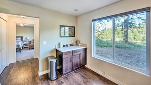 A modern kitchen with dark wood cabinets, a countertop, and a window with a view of trees. - Dreamy Riverside Cabin With Fireplace & Grill (Concrete)