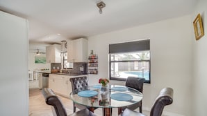 A modern kitchen with white cabinets, a glass dining table, and a view of the outside. - 'space Coast' Getaway w/ Outdoor Pool & Spa! (Palm Bay)