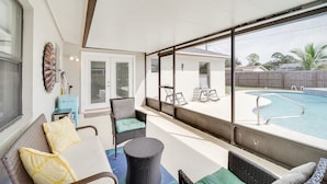 A covered outdoor area with a pool, wicker furniture, and a view of the backyard. - 'space Coast' Getaway w/ Outdoor Pool & Spa! (Palm Bay)