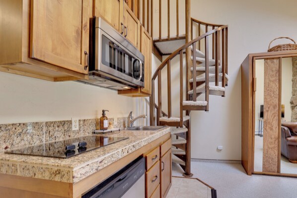 A kitchen with granite countertops, wooden cabinets, a built-in microwave, and a stainless steel sink.