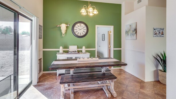 A dining area with a wooden table and benches, a wall clock, a cow skull decoration, and a hanging light fixture. - Inviting Bullhead City Gem: 3 Mi to Colorado River (Bullhead City)