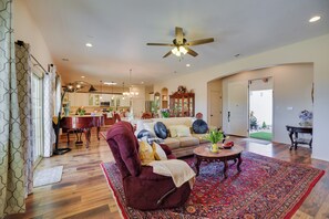 A spacious living room with a red armchair, a patterned rug, and a ceiling fan.