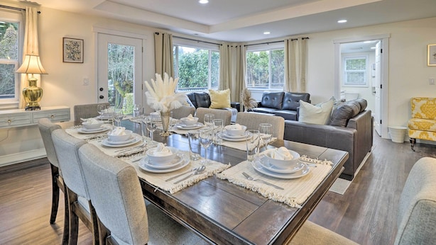 Un coin repas avec une table en bois dressée pour six personnes, entourée de chaises à revêtement gris.