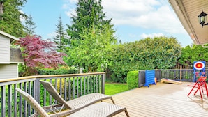 Une terrasse en bois avec des chaises en osier, un jeu de lancer d’anneaux et une petite table.