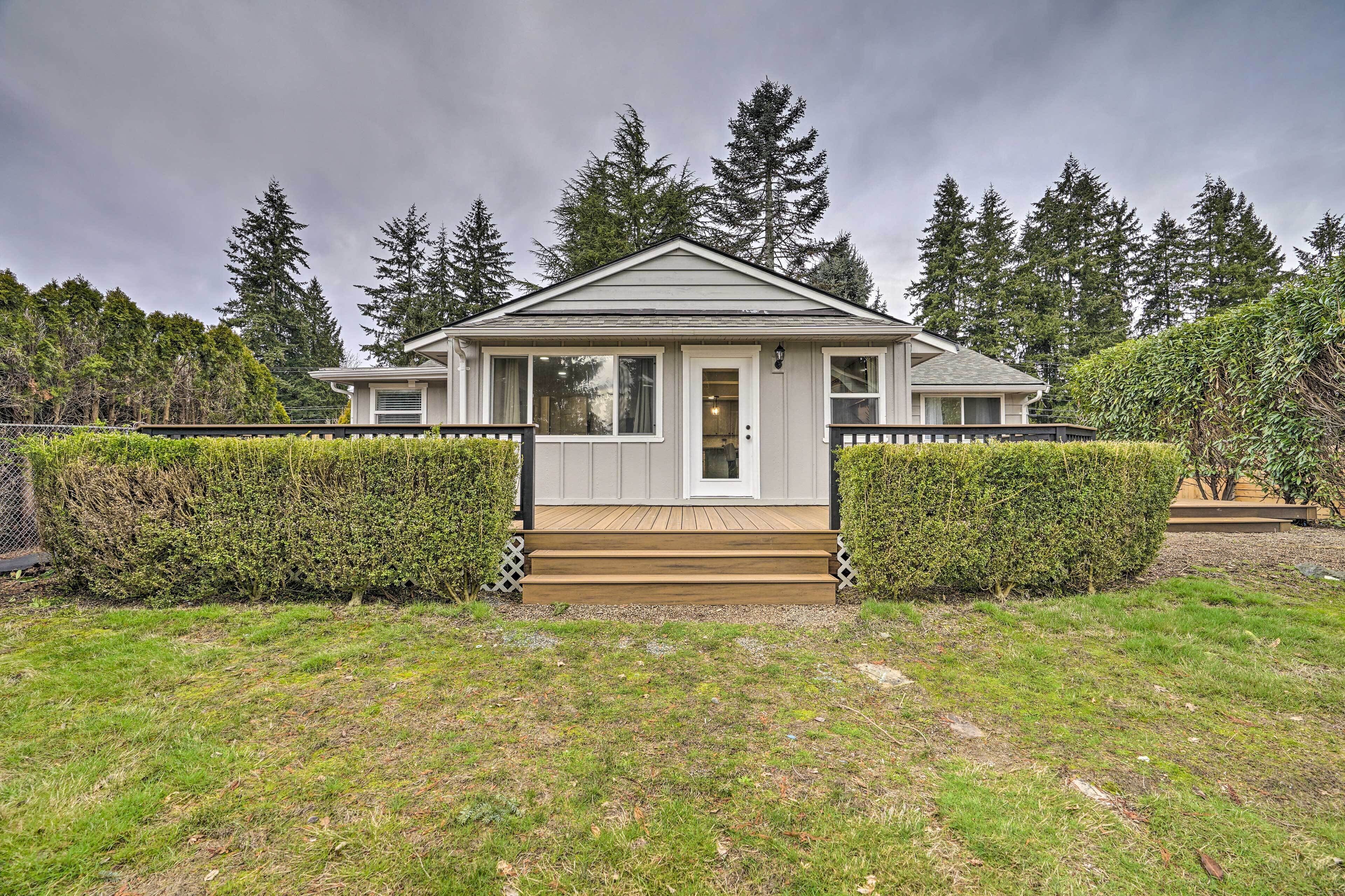 A single-story house with a front porch, surrounded by a well-maintained lawn and tall trees.