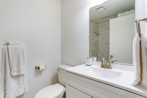 Une salle de bain avec un lavabo blanc, des toilettes et un miroir.