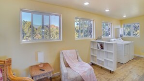A room with large windows, a massage chair, a white laundry station, and a wicker chair. - Kanab Studio Escape: Stargaze, Hike, Relax! (Kanab)