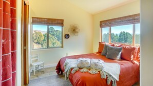 A bedroom with a large bed, two windows with blinds, a chair, and a wall clock. - Kanab Studio Escape: Stargaze, Hike, Relax! (Kanab)