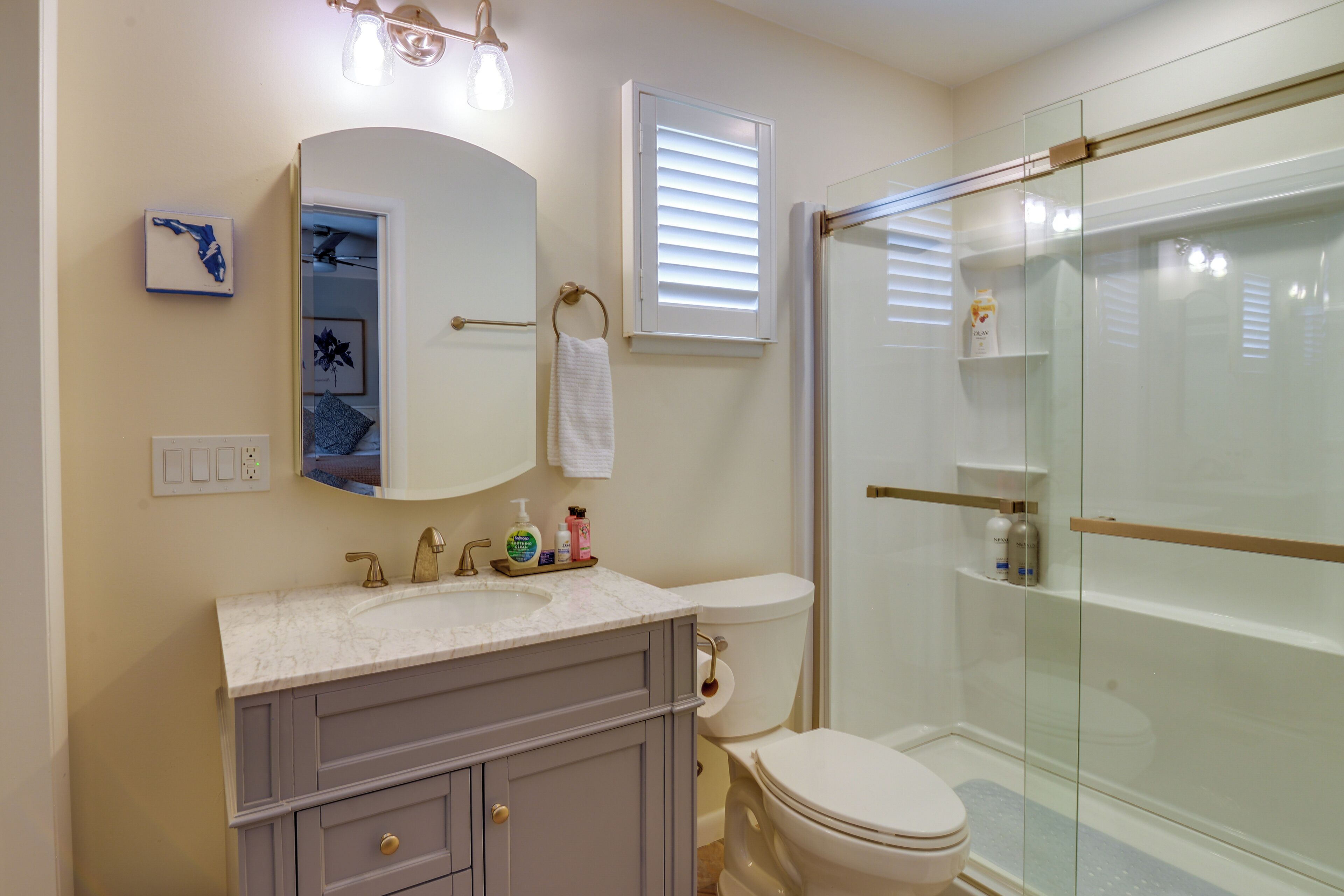 A bathroom with a vanity, toilet, and glass shower enclosure.