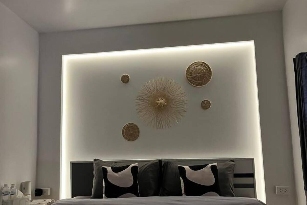 A modern hotel room with a bed, a bedside table, and a wall-mounted light fixture.