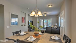 A dining area with a wooden table, chairs, a chandelier, and a potted plant. - Retreat w/ Spacious Patio & Superstition Mtn Views (Gold Canyon)