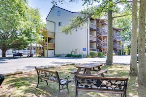 A two-story building with a balcony on the upper floor, a parking area, and picnic tables in the foreground.