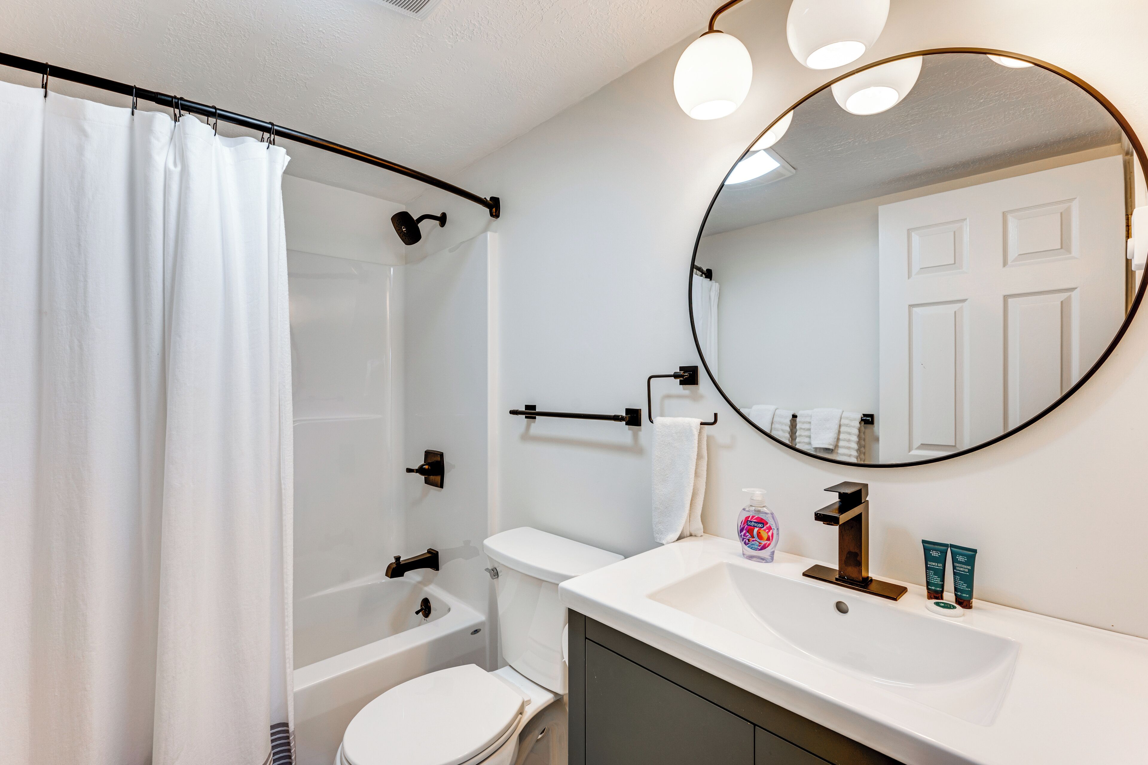 Une salle de bain équipée d’une douche, de toilettes, d’un lavabo et d’un grand miroir.