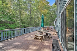 A wooden deck with a table and chairs, surrounded by a railing, overlooking a forested area. - Condo w/ Deck & Grill < 5 Miles to Loon Mountain! (North Woodstock)