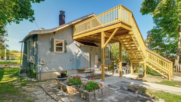 A house with a wooden deck and a staircase leading to a covered patio area. - Vintage Charlevoix Home w/ Deck Near Round Lake! (Charlevoix)