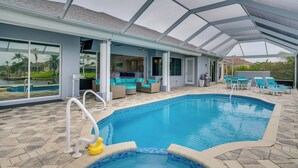 A covered outdoor swimming pool with lounge chairs and a patio area. - Canal-view Oasis w/ Grill in Cape Coral! (Cape Coral)