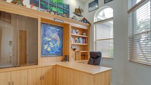 A spacious office with a wooden desk, a bookshelf, and a large framed painting. - Canal-view Oasis w/ Grill in Cape Coral! (Cape Coral)