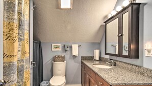 A bathroom with a toilet, sink, vanity, and a large mirror.