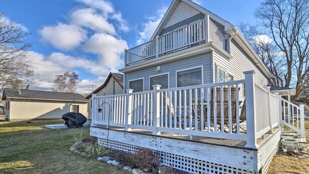 A two-story house with a white exterior, a covered porch, and a small deck.