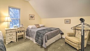 A bedroom with a bed, a desk, a chair, and a window.