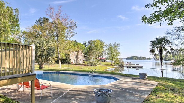 A backyard with a swimming pool, a wooden deck, and a view of a lake. - Lush Gilbert House w/ Outdoor Oasis on Lake Murray (Gilbert)