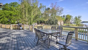 A wooden deck with a glass table and chairs, overlooking a body of water and trees. - Lush Gilbert House w/ Outdoor Oasis on Lake Murray (Gilbert)