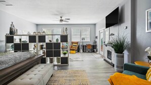 A modern living room with a sofa, a coffee table, a fireplace, and a TV mounted on the wall. - Clearwater Vacation Rental w/ Furnished Patio! (Clearwater)