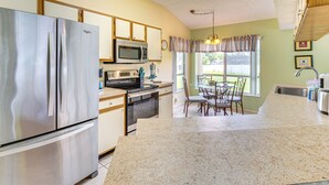 A kitchen with a stainless steel refrigerator, microwave, and stove. There is a dining area with a table and chairs.