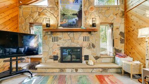 Une cheminée en pierre, une affiche, un téléviseur et un tapis coloré dans une pièce en bois.