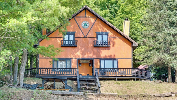 A wooden cabin with a front porch, two balconies, and a chimney.