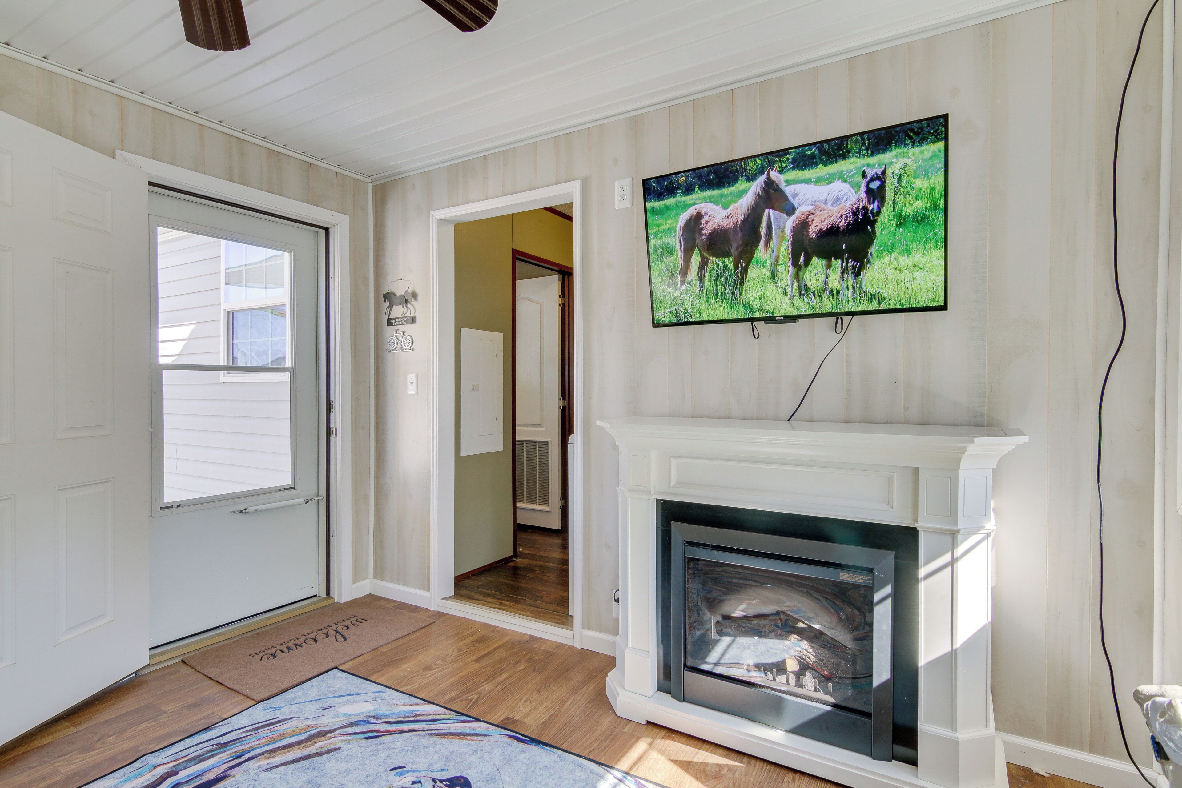 A living room with a fireplace, a television mounted above it, and a door leading to another room.