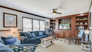 Ein Wohnzimmer mit einem blauen Sofa, einem Holztisch, einem Fernseher und einem Bücherregal.