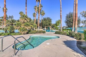 A swimming pool with metal railings, surrounded by palm trees and a gazebo.