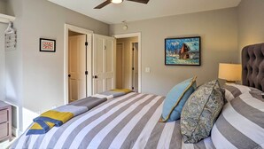 Een slaapkamer met een bed, een plafondventilator, een schilderij en een deur.