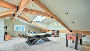 Een ruime kamer met een pooltafel, tafelvoetbal en boekenkasten.