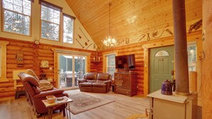 A log cabin interior with a fireplace, leather furniture, and a television.