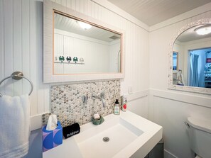 Ein Badezimmer mit einem weißen Waschbecken, einem Spiegel und einer gefliesten Rückwand.