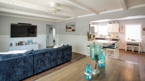 Een woonkamer met een bank, een televisie en een keuken op de achtergrond.