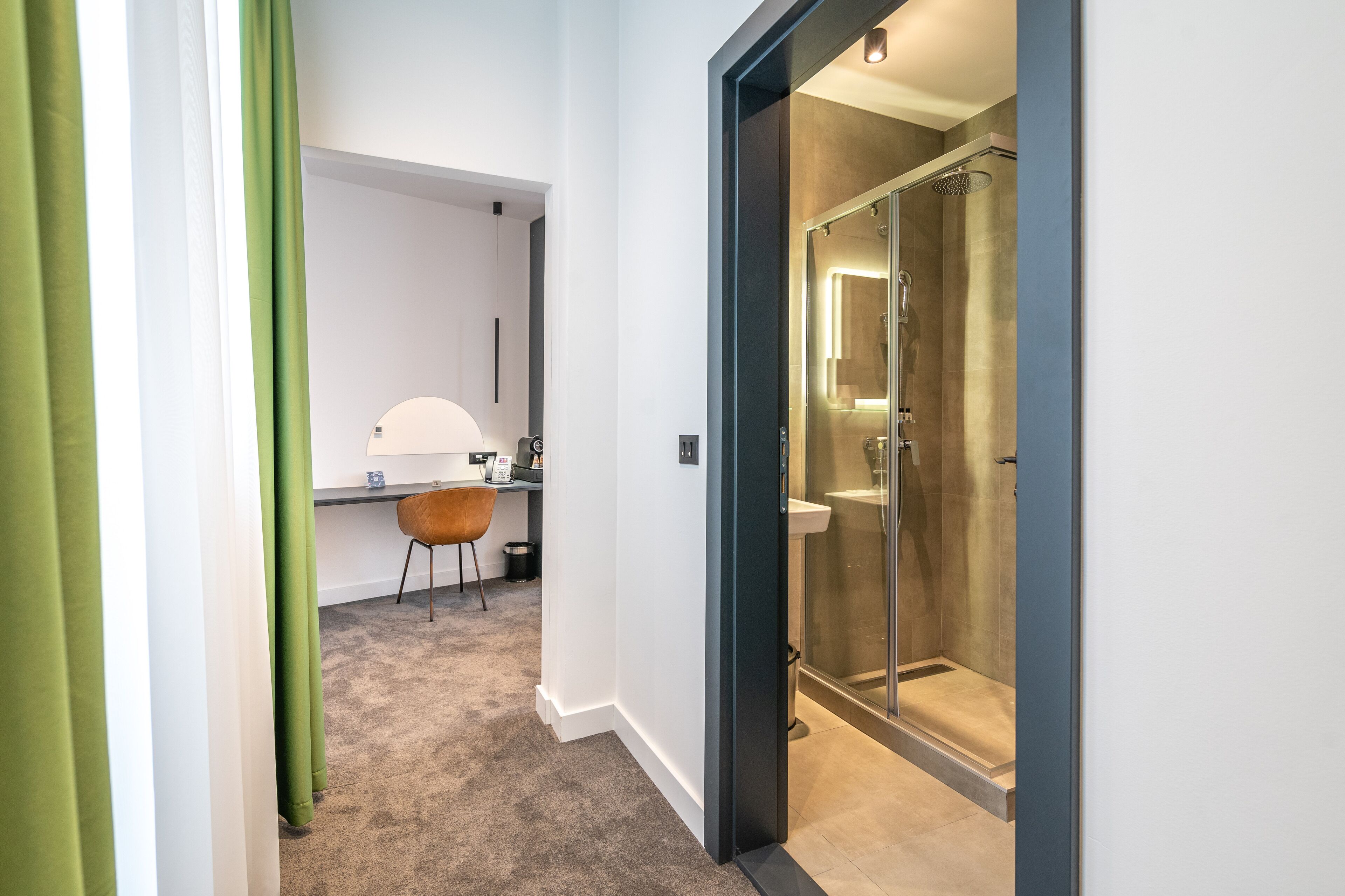 A modern bathroom with a glass shower enclosure, a sink, and a chair.