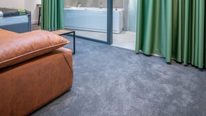 Una habitación de hotel moderna con tragaluz, una cama grande, un separador de vidrio y un baño con bañera.